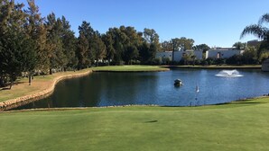 A golf course with a pond, trees, and a building in the background. - Penthouse with sunny roof terrace, seaview, close to bars/restaurants, air con (Mijas)