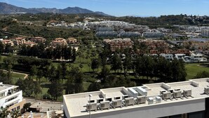 A modern building with multiple air conditioning units on the roof, a swimming pool, and a view of a residential area with houses and greenery. - Penthouse with sunny roof terrace, seaview, close to bars/restaurants, air con (Mijas)