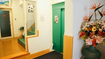 A hotel lobby with a green door, a panda decoration, and a floral arrangement.