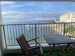 A balcony with a view of the sea, a chair, and a table. - Shinnishiki Hotel (Shirahama)