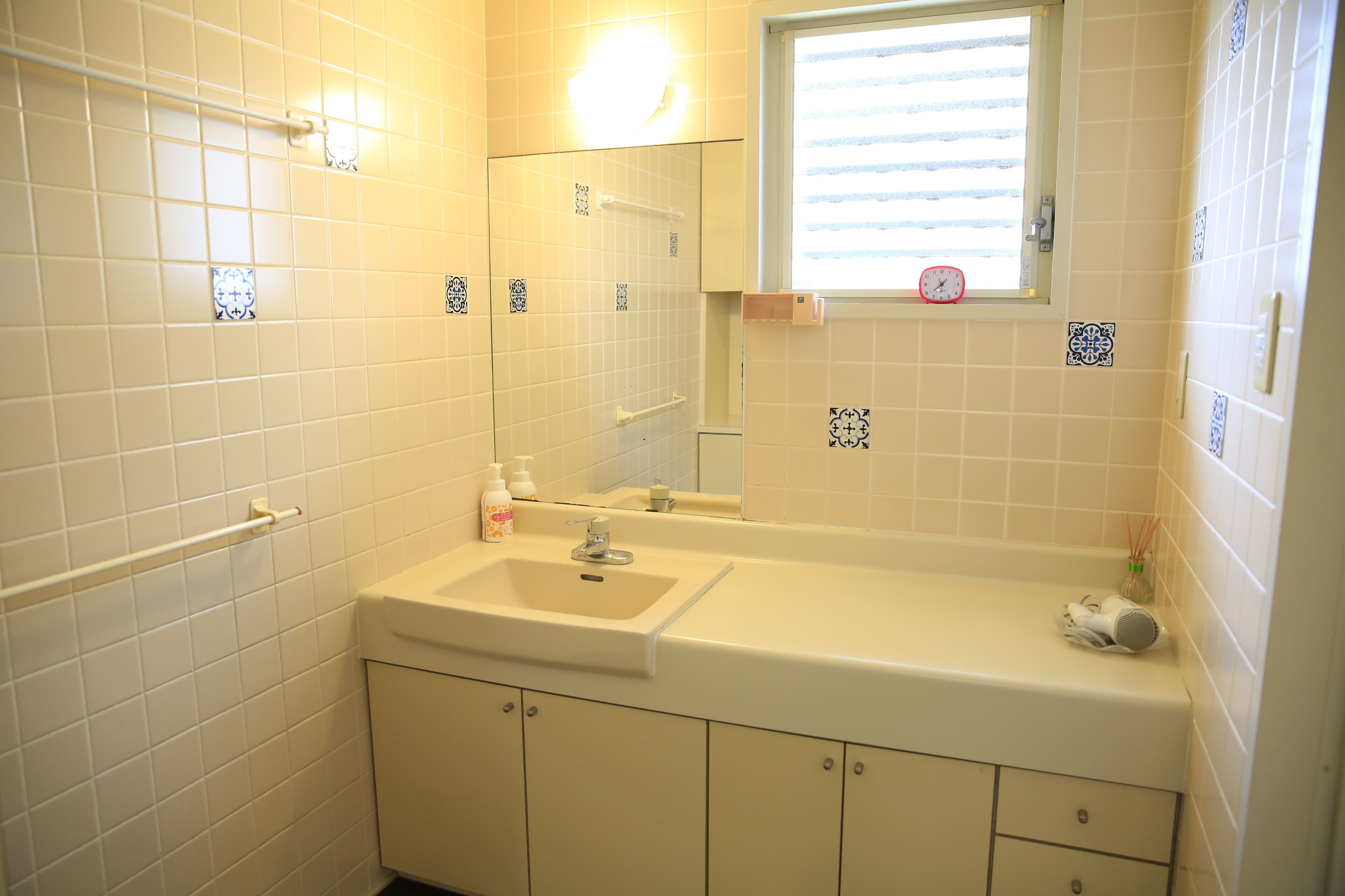 A bathroom with a sink, mirror, and window.