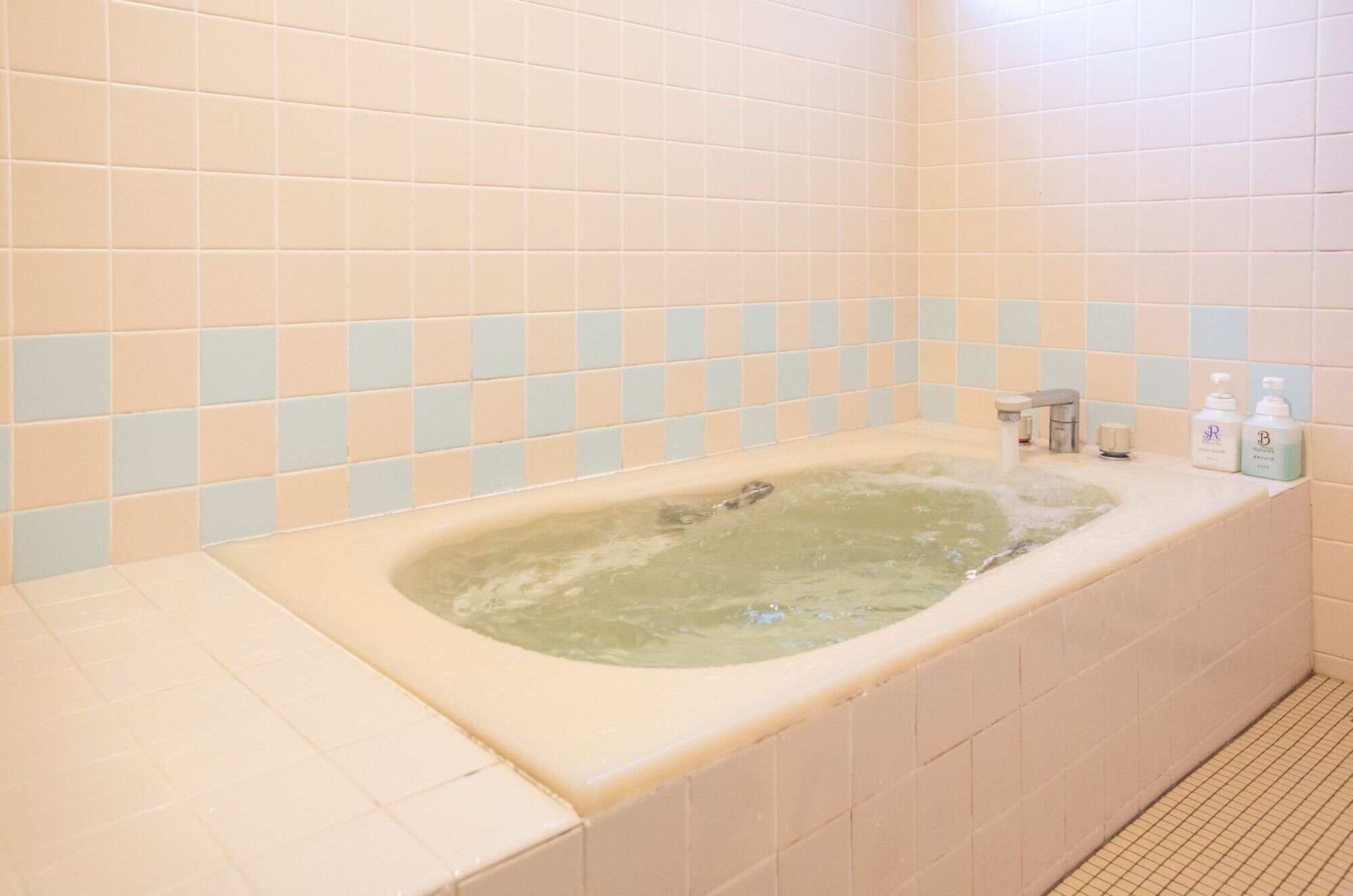 A bathroom with a bathtub, tiled walls, and a shower area.