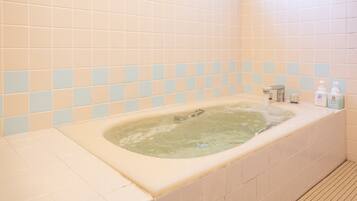 A bathroom with a bathtub, tiled walls, and a shower area.