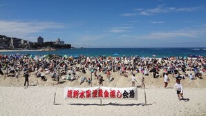 Praia movimentada com pessoas se bronzeando e brincando.