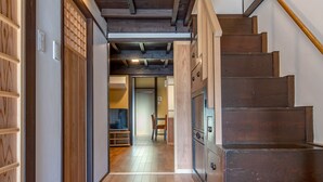 Un intérieur en bois comprenant un escalier, un couloir et une pièce avec une chaise et une table.
