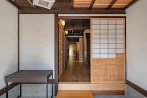 A traditional Japanese room with a sliding door, a small table, and a wooden bench. - Obama Machiya Stay (Obama)