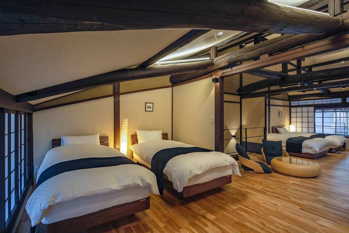 Una habitación tradicional japonesa con dos camas, suelo de madera, esteras de tatami y una puerta corredera.
