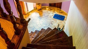 A spiral staircase with wooden balusters and a tiled floor leading to a landing area with a blue mat. - Villa in Biטvre with garden (Bièvre)