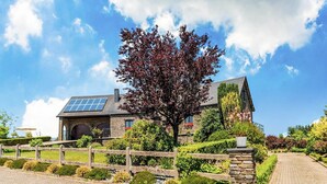 A large house with a stone facade, a solar panel roof, and a well-maintained garden with a wooden fence. - Villa in Biטvre with garden (Bièvre)