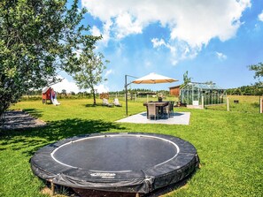 A backyard with a trampoline, a playhouse, a slide, a picnic table, and a greenhouse. - Villa in Biטvre with garden (Bièvre)