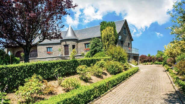 A stone building with a conical roof, surrounded by well-maintained hedges and a cobblestone pathway. - Villa in Biטvre with garden (Bièvre)