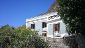 Un immeuble de deux étages à la façade bleu clair, doté d’un balcon et d’un escalier en pierre menant à l’entrée.