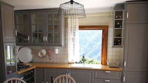 Une cuisine avec une table à manger, des chaises, une bouteille de vin et un panier.