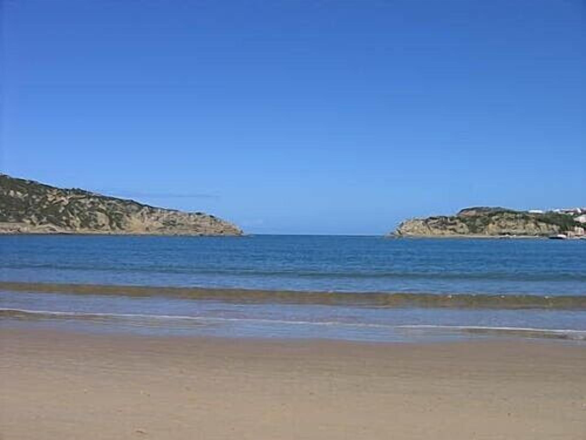 Ein Strand mit klarem, blauem Wasser und sandigem Ufer.