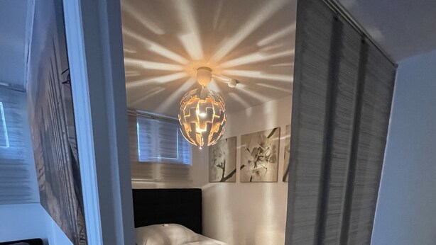 Un dormitorio moderno con cama, lámpara en forma de globo y arte abstracto en la pared.
