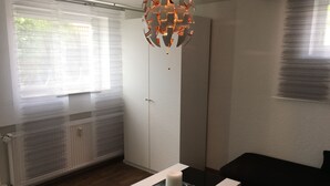 Una habitación moderna con una mesa de vidrio, una vela blanca, un sofá negro y un candelabro original.