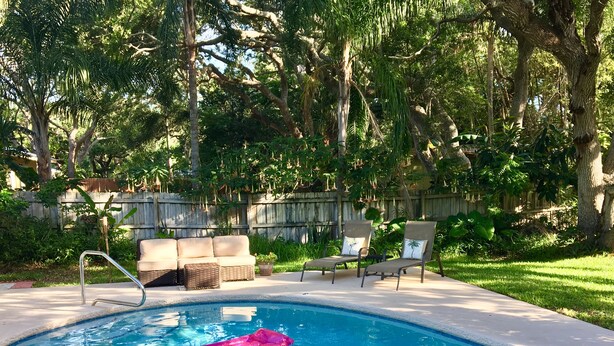 A backyard with a swimming pool, lounge chairs, and a wooden fence. - Walk to Beach! Family Beach House, Game room!  Sunset View! (Daytona Beach)