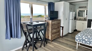 Ein Zimmer mit Esstisch, Stühlen, Fernseher, Küchenzeile und einem Bett.