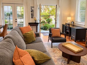 Ein Wohnzimmer mit einer Couch, Sesseln, einem Couchtisch und einem Schreibtisch mit einer Lampe.