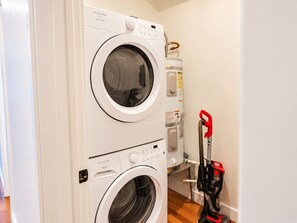 Une machine à laver et un sèche-linge à chargement frontal, placés l’un sur l’autre dans une buanderie.