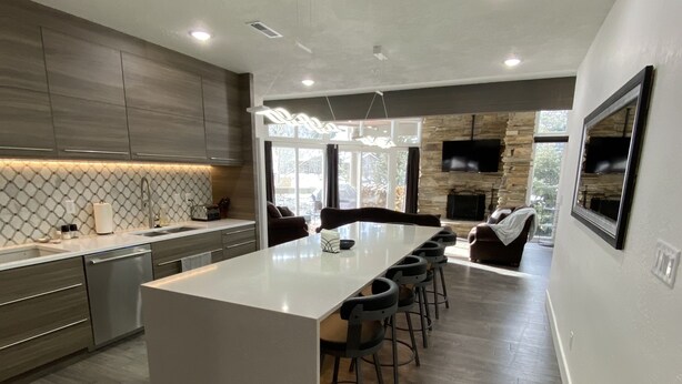 A modern kitchen with a central island, bar stools, and a stone accent wall. - Powder Run Premier Unit - All NEW Corner unit with views, Private Hot Tub !! (Park City)