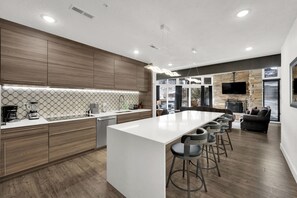 A modern kitchen with a central island, bar stools, and a stone fireplace.