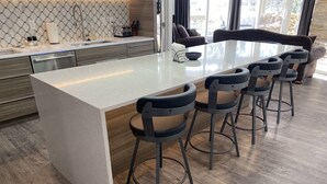 A modern kitchen with a central island, bar stools, and a dining table. - Powder Run Premier Unit - All NEW Corner unit with views, Private Hot Tub !! (Park City)