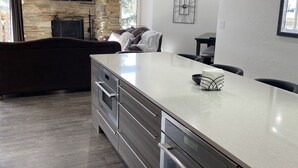 A modern kitchen with a large island, built-in oven, and a stone accent wall. - Powder Run Premier Unit - All NEW Corner unit with views, Private Hot Tub !! (Park City)