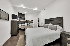 A modern bedroom with a large bed, a desk, and a television.