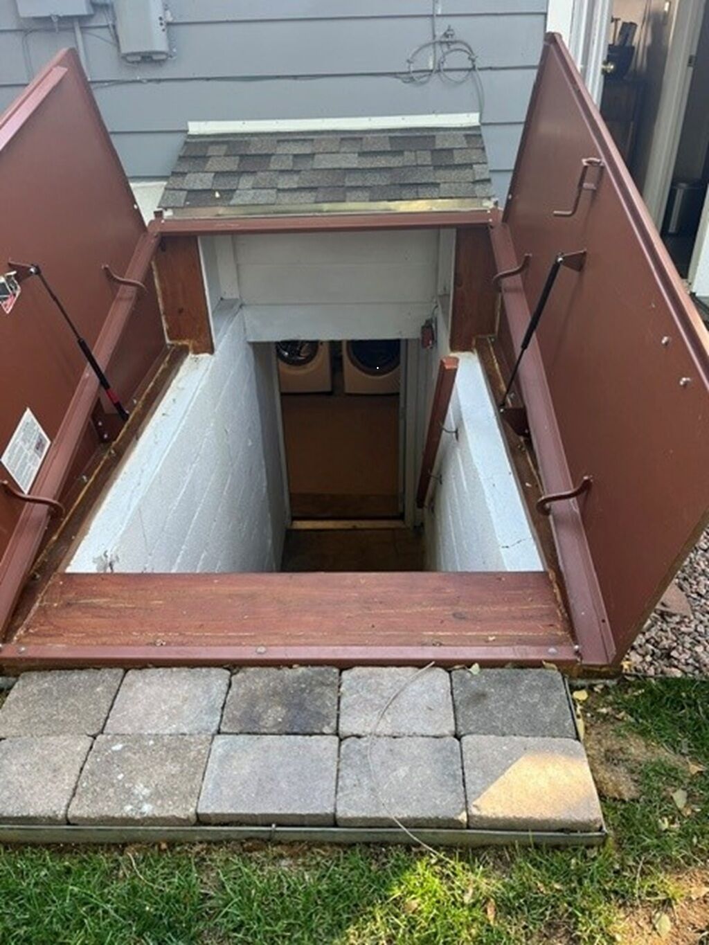 A small, enclosed outdoor space with a wooden floor and a metal roof, accessible via a set of steps.