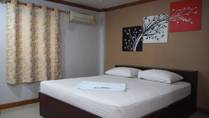 A neatly made bed with a white comforter and pillows, a floral-patterned curtain, and two wall art pieces depicting branches. - Rimmueng Resort (Phanom Sarakham)