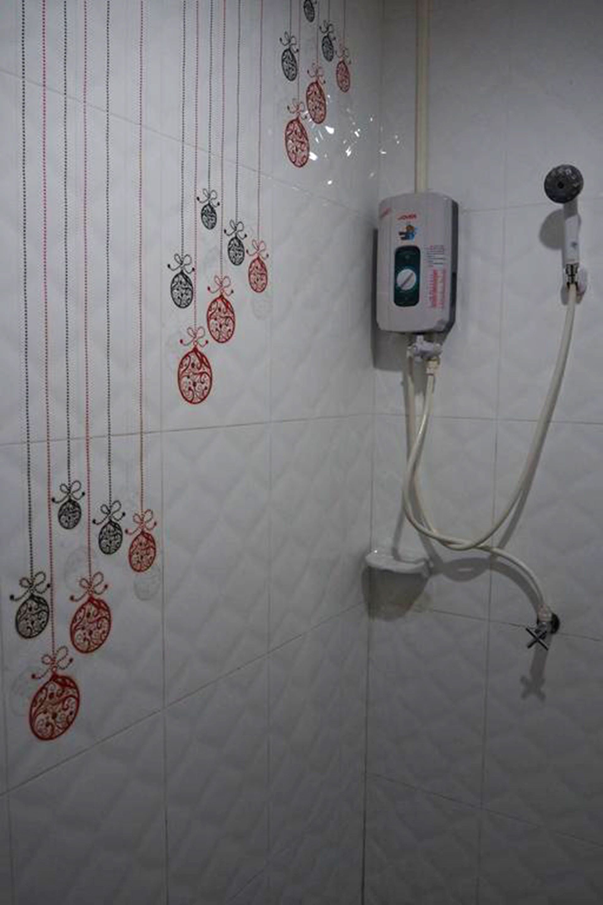 Un baño con ducha, dispensador de jabón en la pared y adornos colgantes decorativos.