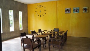 A room with a yellow wall, a clock, and three framed pictures. - Rimmueng Resort (Phanom Sarakham)