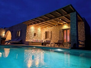 Ein Steinhaus mit Pool, Außenbereich mit Sitzgelegenheiten und einer überdachten Terrasse.