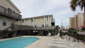 A swimming pool with lounge chairs and a covered deck area.