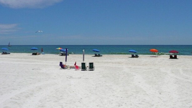 A beach with umbrellas and lounge chairs.
