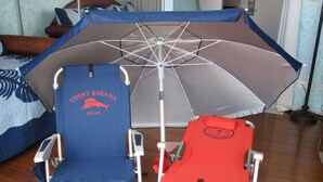 Two beach chairs with umbrellas, one blue and one red, in a room with wooden flooring. - Ocean View Studio - Polu Hale - 2 min Walk from Beach (Honolulu)