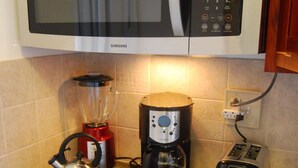 A kitchen with a microwave, coffee maker, kettle, toaster, and a dishwasher. - Ocean View Studio - Polu Hale - 2 min Walk from Beach (Honolulu)