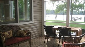 A covered patio area with a wicker sofa, two chairs, and a small table. - Modern St Michaels estate -Pier, Pool, Gas fire pit, Bikes, Kayaks (Easton)