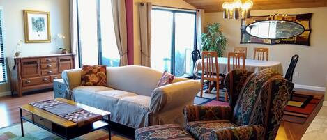 Una sala de estar con sofá, sillón, mesa de centro y un comedor con sillas y una mesa.