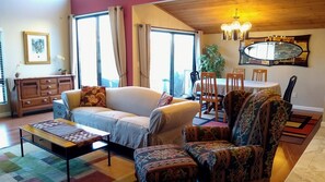 Ein Wohnzimmer mit Sofa, Sessel, Couchtisch und einem Essbereich mit Stühlen und Tisch.