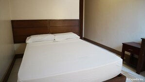 Una cama bien hecha con sábanas blancas en una habitación de hotel.