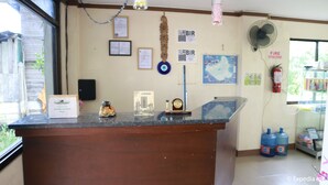 Un mostrador de recepción con encimera de madera, un certificado enmarcado, una figurita pequeña y un mapa en la pared.