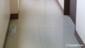 Un pasillo con un bote de basura verde y una botella de agua en el suelo.