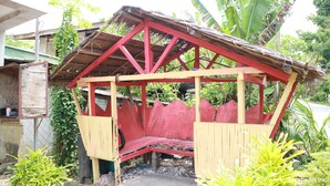 Una estructura de madera con techo rojo y asientos en banco.