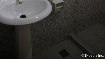 Un baño con lavamanos blanco, inodoro y zona de ducha.