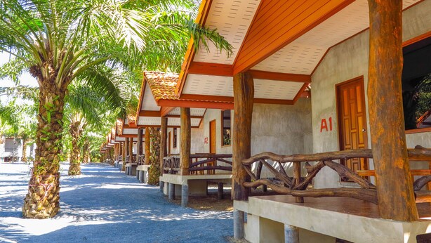 A row of wooden cabins with palm trees in front, each cabin has a number on the door. - Palmsuay Resort (Khao Saming)