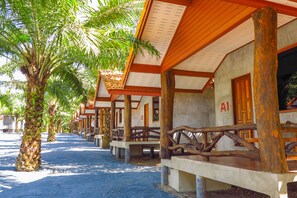 A row of wooden cabins with palm trees in front, each cabin has a number on the door.