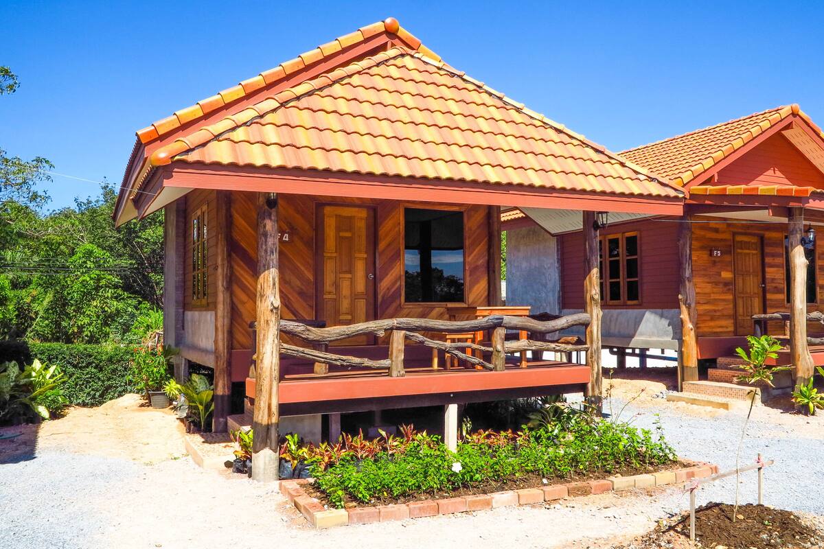Una cabaña de madera con techo de tejas, un porche y un jardín.