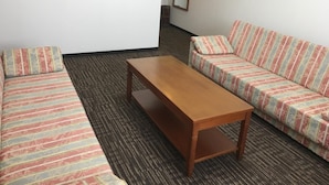Ein Zimmer mit einem gestreiften Sofagarnitur, einem Holztisch und einem Teppichboden.